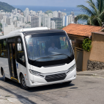 Micro-ônibus do transporte coletivo de Santos percorrendo uma via em área de morro, sem texto ou placas legíveis na imagem