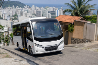 Micro-ônibus do transporte coletivo de Santos percorrendo uma via em área de morro, sem texto ou placas legíveis na imagem
