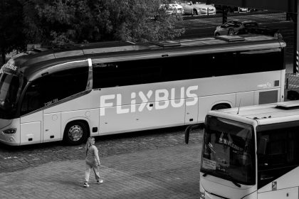 Ônibus rodoviário estacionado em um terminal, com passageiros nas proximidades.