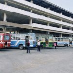 Terminal rodoviário urbano com vários ônibus coloridos estacionados.