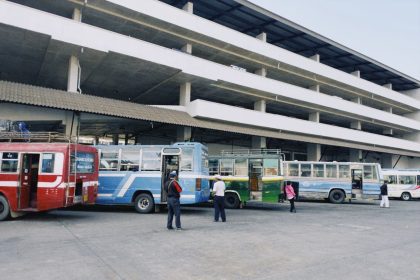 Terminal rodoviário urbano com vários ônibus coloridos estacionados.