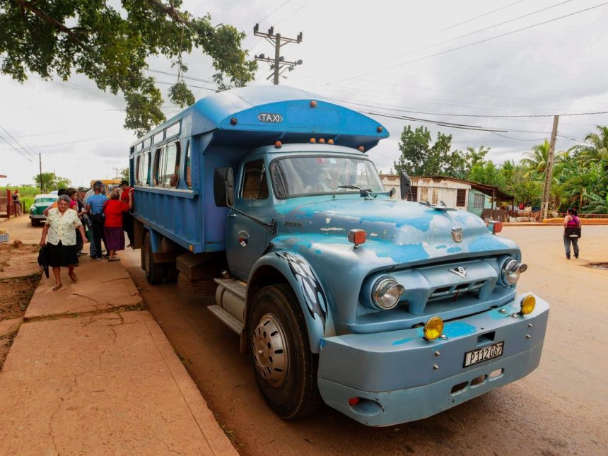 Ônibus azul de transporte público parado em uma rua, com passageiros embarcando e desembarcando.