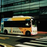 Ônibus urbano atravessa uma faixa de pedestres em uma via movimentada da cidade.
