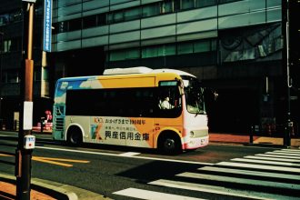 Ônibus urbano atravessa uma faixa de pedestres em uma via movimentada da cidade.
