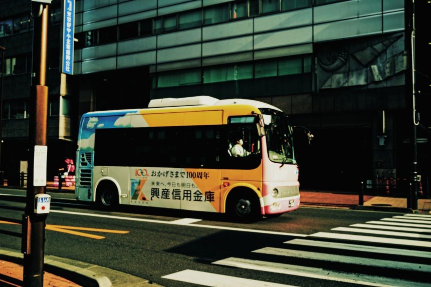 Ônibus urbano atravessa uma faixa de pedestres em uma via movimentada da cidade.