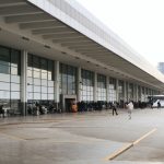 Terminal rodoviário movimentado, com passageiros aguardando e ônibus estacionados.