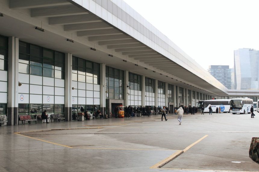 Terminal rodoviário movimentado, com passageiros aguardando e ônibus estacionados.